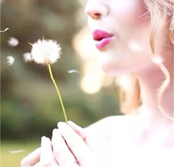 Девушка дует на одуванчик