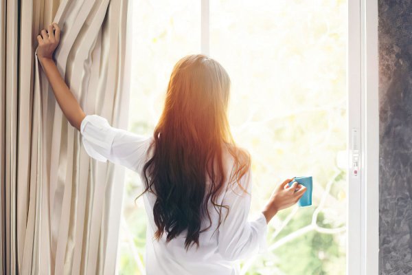 Женщина открывает шторы