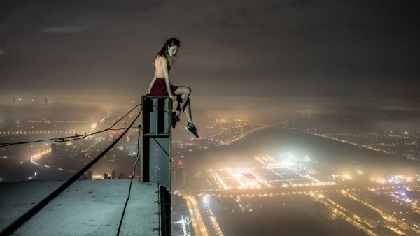 Девушка сидит на краю крыши