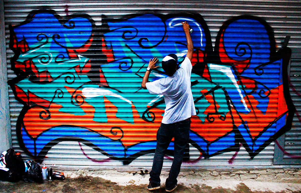 Рисует граффити на стене