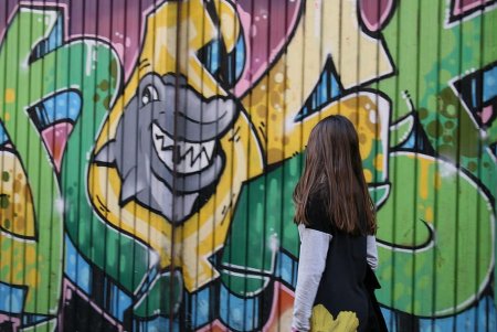 Подросток рисует на стене