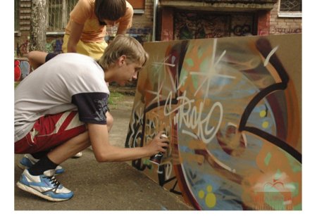 Подросток рисует на стене