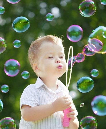 Ребенок надувает мыльные пузыри